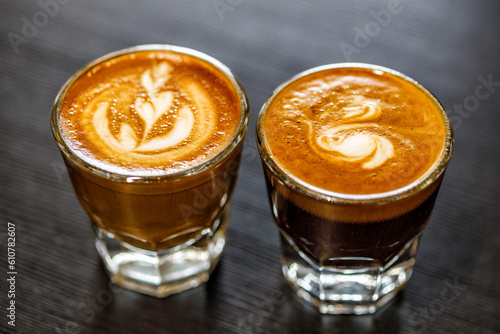 Two cortado coffee drinks in espresso glasses featuring latte art