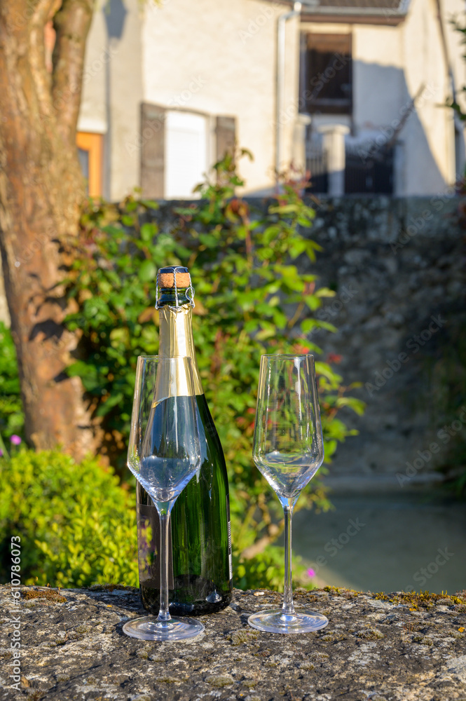 Tasting of premier cru sparkling white wine with bubbles champagne with view on old houses of Hautvillers, where lived Benedictine monk how developed champagne wine, France.