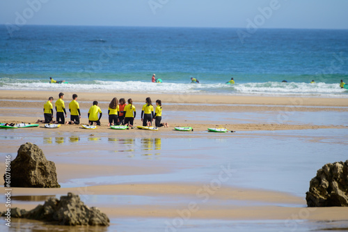 Young surfers train on Playa de Palombina Las Camaras in Celorio, Green coast of Asturias, North Spain with sandy beaches, cliffs, hidden caves, green fields and mountains photo