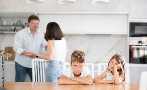 Family problem, conflict and people concept - sad children sitting at the table their parents quarreling at home