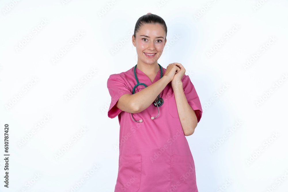 Dreamy young caucasian doctor woman wearing pink uniform over white background with pleasant expression, closes eyes, keeps hands crossed near face, thinks about something pleasant Dreamy young caucasian doctor woman wearing pink uniform over white background with pleasant expression, closes eyes, keeps hands crossed near face, thinks about something pleasant