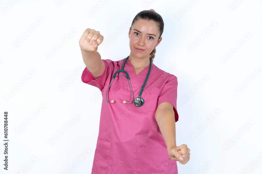 Portrait of charming young caucasian doctor woman wearing pink uniform over white background , smiling broadly while holding hands over her head. Confidence and relax concept. Portrait of charming young caucasian doctor woman wearing pink uniform over white background , smiling broadly while holding hands over her head. Confidence and relax concept.