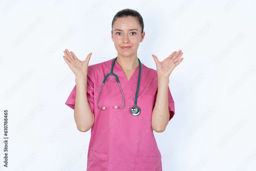 Joyful excited lucky young caucasian doctor woman wearing pink uniform over white background cheering, celebrating success, screaming yes with clenched fists Joyful excited lucky young caucasian doctor woman wearing pink uniform over white background cheering, celebrating success, screaming yes with clenched fists