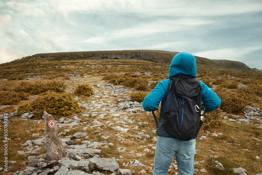 Man in blue jacket hiking on top of the mountain at Burren National Park in County Clare, Ireland