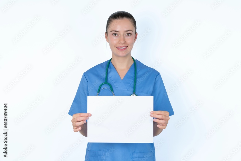 Happy young caucasian doctor woman wearing medical uniform over white background Holding Empty Paper Board Advertising Offer Text Standing. Autumn Advertisement Banner. Happy young caucasian doctor woman wearing medical uniform over white background Holding Empty Paper Board Advertising Offer Text Standing. Autumn Advertisement Banner.