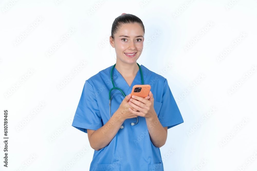 young caucasian doctor woman wearing medical uniform over white background Mock up copy space. Using mobile phone, typing sms message young caucasian doctor woman wearing medical uniform over white background Mock up copy space. Using mobile phone, typing sms message