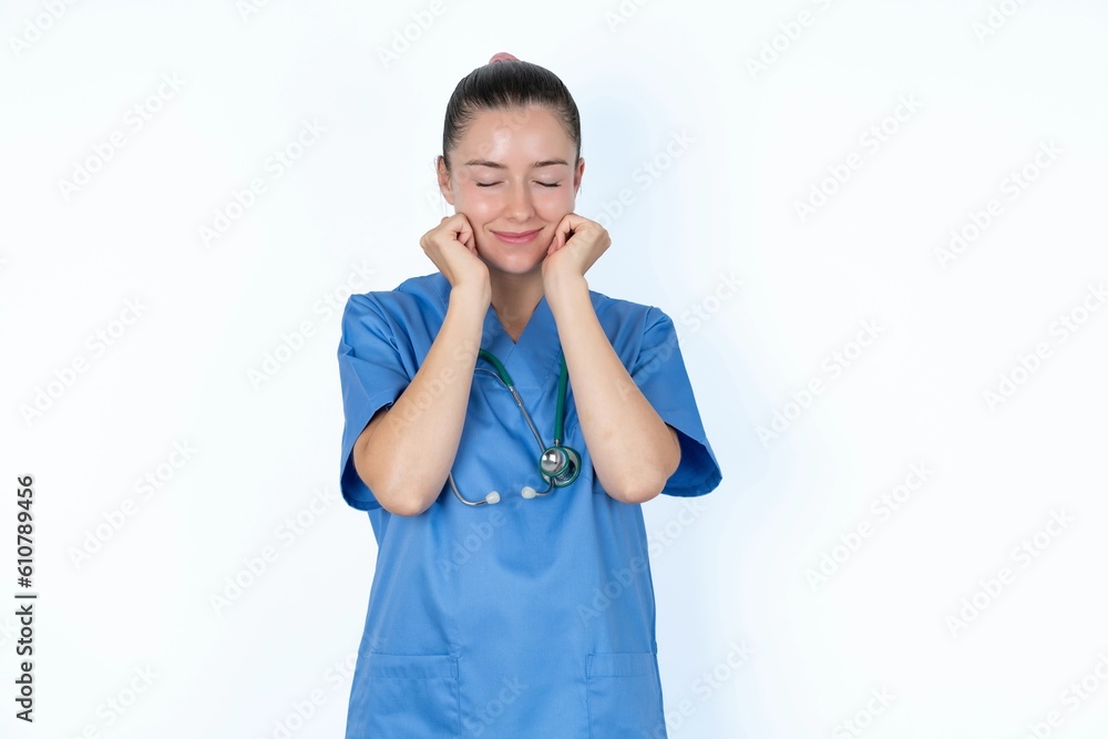 young caucasian doctor woman wearing medical uniform over white background grins joyfully, imagines something pleasant, copy space. Pleasant emotions concept. young caucasian doctor woman wearing medical uniform over white background grins joyfully, imagines something pleasant, copy space. Pleasant emotions concept.