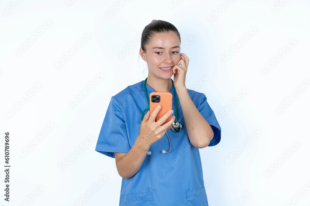 Afraid funny young caucasian doctor woman wearing medical uniform over white background holding telephone and bitting nails