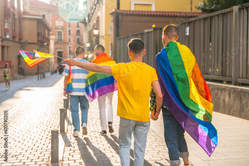 Gay pride party in the city, men walking with their backs towards the demonstration with the rainbow flags, lgbt concept © unai