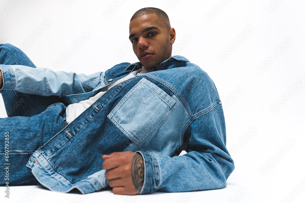 African American man wearing a denim jacket and jeans striking a pose on the floor. Isolated against a white background. High-quality 4k footage African American man wearing a denim jacket and jeans striking a pose on the floor. Isolated against a white background. High-quality 4k footage