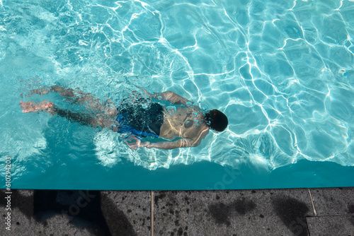 Looking down at a man swimming under water in a pool
