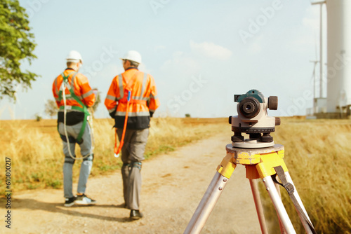Back view Architect male surveyor team working with surveyor's telescope to measure heights of walk in areas, surveying wind generating fields, to plan road construction with professional tools.