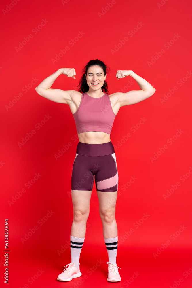 Confident sportswoman showing her biceps muscles, smiling looking at camera
