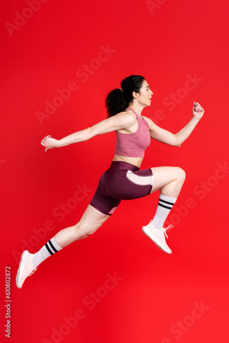 Focused competitive determined sportswoman jumping high, fast running