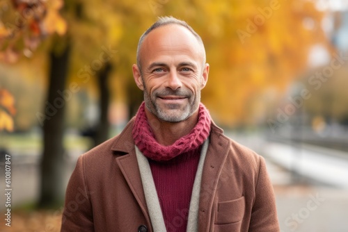 Handsome middle-aged man in a coat and scarf in an autumn park