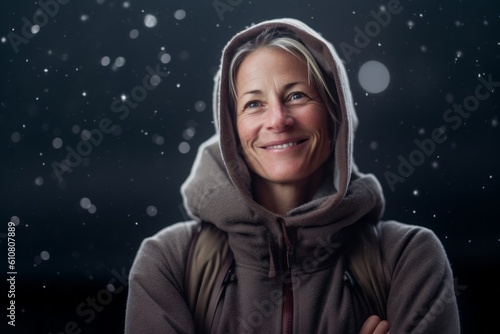 Portrait of smiling woman wearing hoodie with snowfall in background
