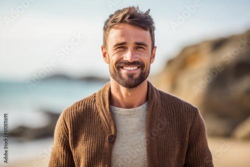 Portrait of handsome man smiling at camera on the beach in autumn © Leon Waltz