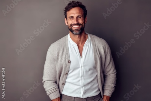 Cheerful man looking at camera and smiling while standing against grey background