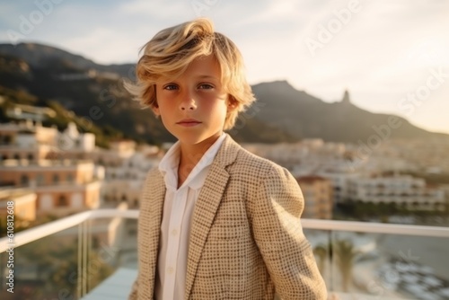 portrait of a beautiful blond boy in a beige jacket on the terrace of a modern house