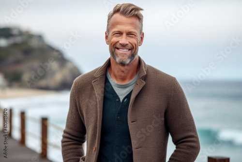 Portrait of a handsome mature man standing on a pier at the beach