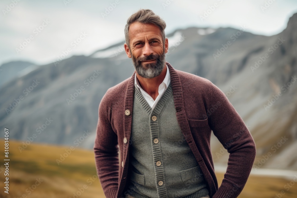 Portrait of a handsome mature man with a beard standing in the mountains.