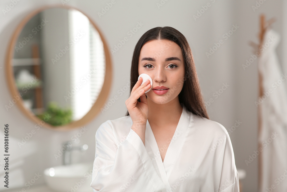 Beautiful woman removing makeup with cotton pad indoors Beautiful woman removing makeup with cotton pad indoors