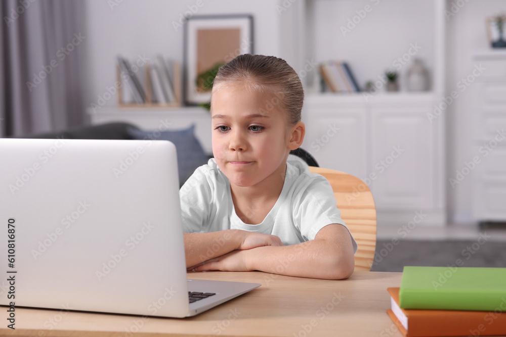 Little girl using laptop at table indoors. Internet addiction Little girl using laptop at table indoors. Internet addiction