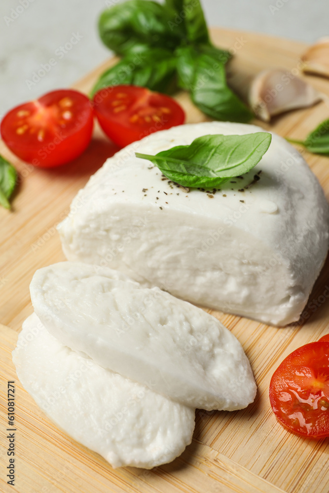 Delicious mozzarella with tomatoes and basil leaves on wooden board, closeup Delicious mozzarella with tomatoes and basil leaves on wooden board, closeup
