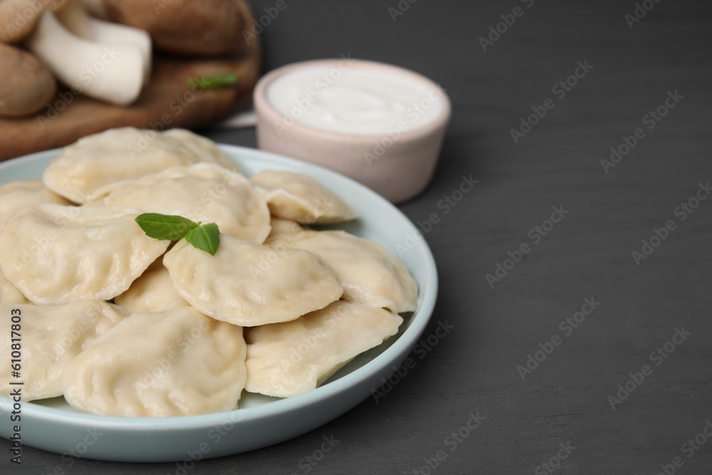 Plate of delicious dumplings (varenyky) with mushrooms on grey wooden table, closeup. Space for text Plate of delicious dumplings (varenyky) with mushrooms on grey wooden table, closeup. Space for text