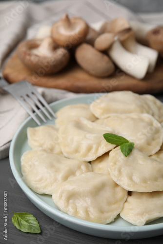 Plate of delicious dumplings (varenyky) with mushrooms served on grey wooden table, closeup
