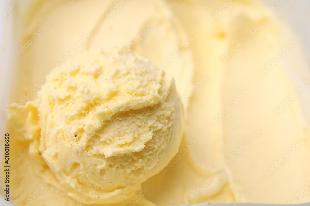 Scoop of delicious vanilla ice cream in container, closeup