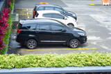 high angle view of suv and hatchback cars in the parking lot of a mall with green grass in foreground. black and white cars