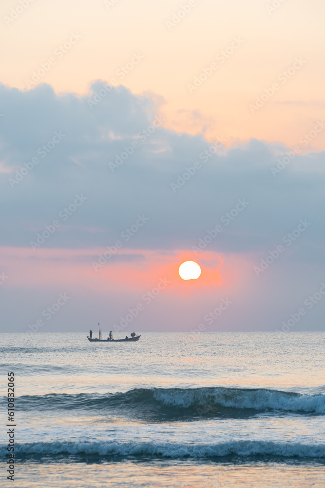 Landscape of small fishing boats of Vietnamese fishermen fishing at dawn in the sea, with rising sun, clouds and sky. Seascape at sunrise and sunset in beautiful yellow and orange.