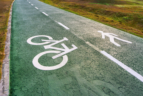 Lanes for joggers and cyclists made of green recycled rubber. Lanes are divided into two sections by dividing lines and white graphic icons.