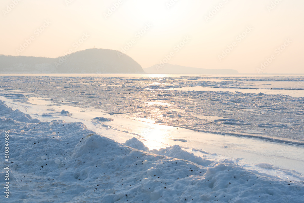 Winter beautiful landscape of frozen Japan Sea covered with ice and snow on a sunny day. Beauty of nature concept. Postcard from Russia with selective focus