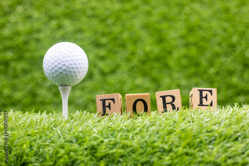 Foto A golf ball with the word FORE writen on it is sitting on green grass