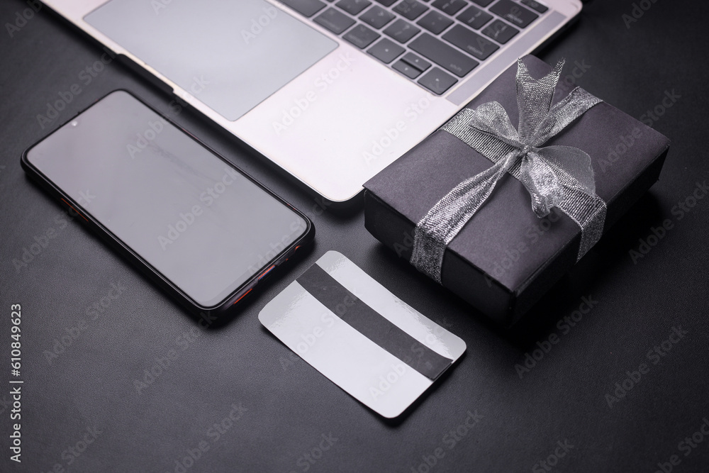 Creative composition of Black Friday Sale concept. Laptop, gift box, credit card and smartphone on black background. Black monochromatic flatlay on black background with copy space Creative composition of Black Friday Sale concept. Laptop, gift box, credit card and smartphone on black background. Black monochromatic flatlay on black background with copy space