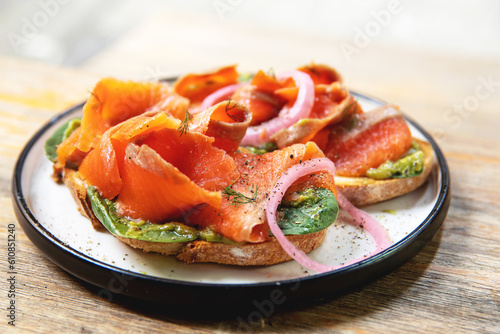 Delicious toasts with smoked salmon, avocado and basil leaves