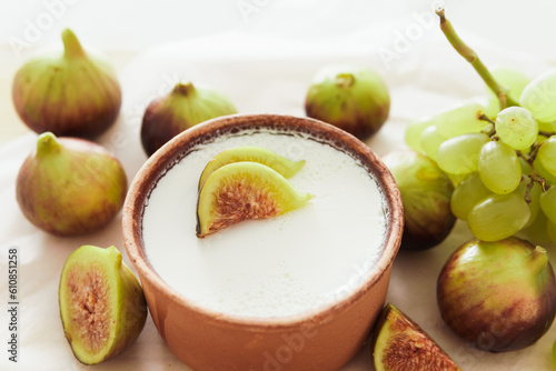 Delicious natural Greek yogurt in clay bowl with figs and grape photo