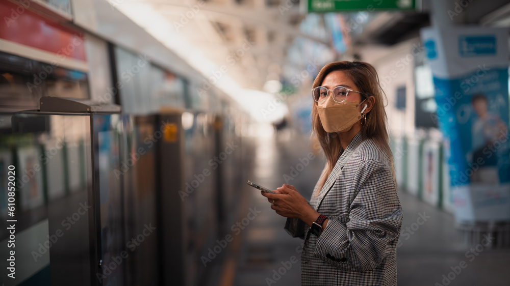 Asian woman business passenger with casual suit using the smart mobile phone in the BTS Skytrain rails or MRT subway for travel in the big city, lifestyle and transportation concept Asian woman business passenger with casual suit using the smart mobile phone in the BTS Skytrain rails or MRT subway for travel in the big city, lifestyle and transportation concept