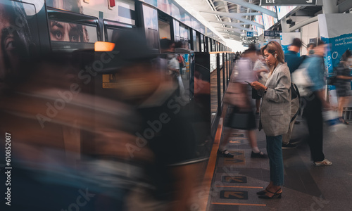 Asian woman business passenger with casual suit using the smart mobile phone in the BTS Skytrain rails or MRT subway for travel in the big city, lifestyle and transportation concept