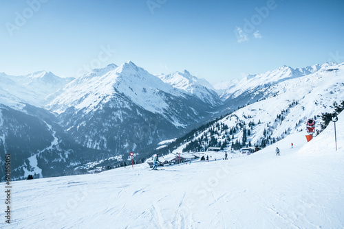 Skiers skiing on snow covered mountain slope against blue sky © Codrin