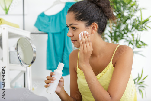 Photos woman using makeup remover as part of her skincare routine