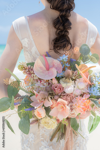 砂浜でドレスを着て、ブーケを背中で持つ女性