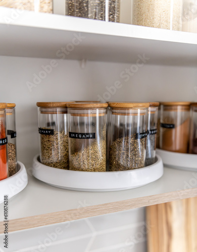 Neatly organized labeled food pantry in a home kitchen with spices in glass wooden spice jars