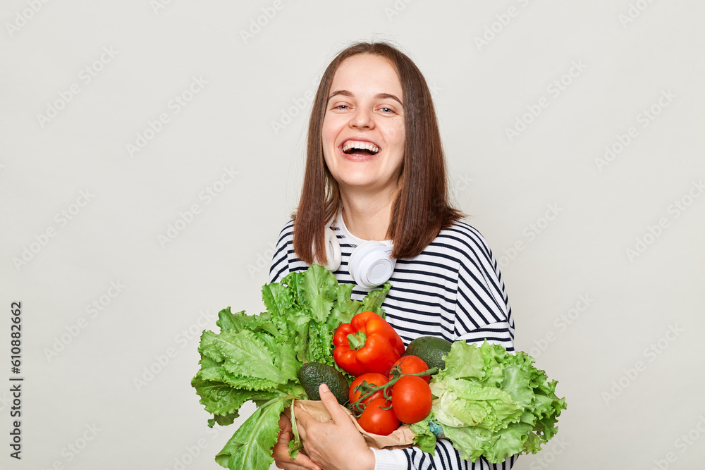 Beautiful smiling woman embraces fresh vegetables posing isolated over white background looking at camera with happy face calls on to eat organic food. Beautiful smiling woman embraces fresh vegetables posing isolated over white background looking at camera with happy face calls on to eat organic food.