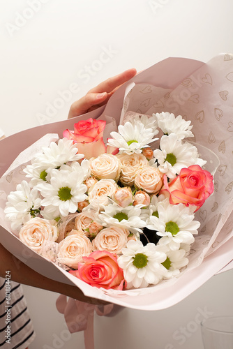 Girl's hands holding beautiful flowers bouquet: bombastic roses, blue eringium, eucalyptus, isolated on white background. Flat lay, top view. Floral composition.