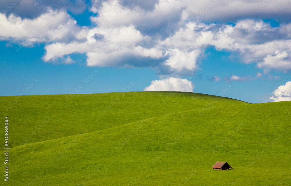 Beautiful landscape with green hills, an old hut and blue sky with clouds. Perfect for wallpaper
