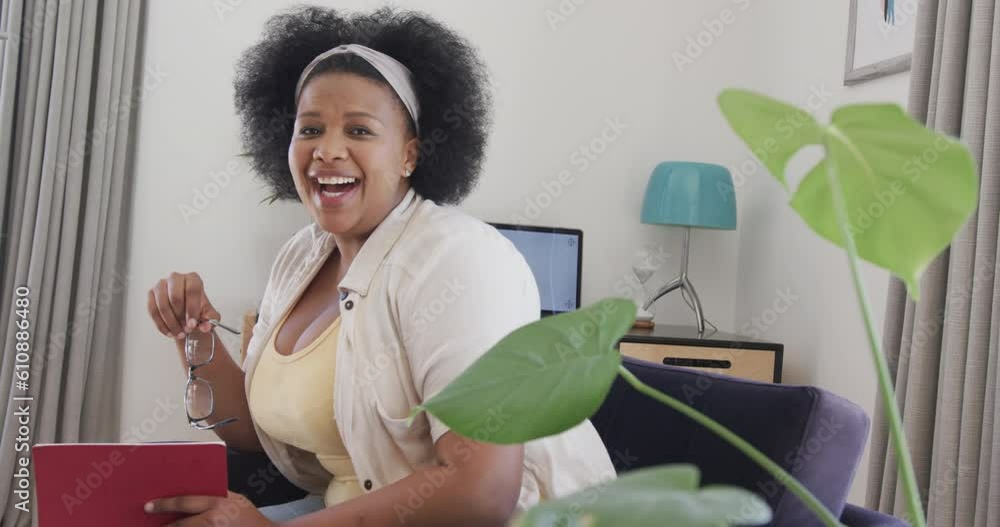 African american plus size woman sitting in armchair and having video call, unaltered, slow motion African american plus size woman sitting in armchair and having video call, unaltered, slow motion