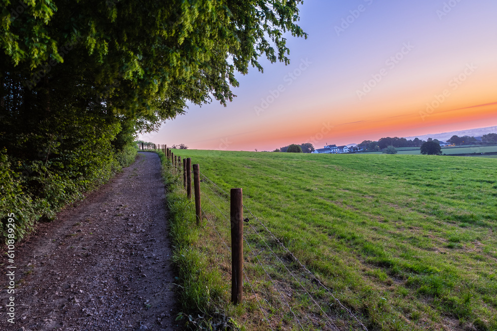 An early morning with a sky full of beautiful colors during sunrise in the rolling hills landscape of Limburg with spectacular views over the typical small villages of this region